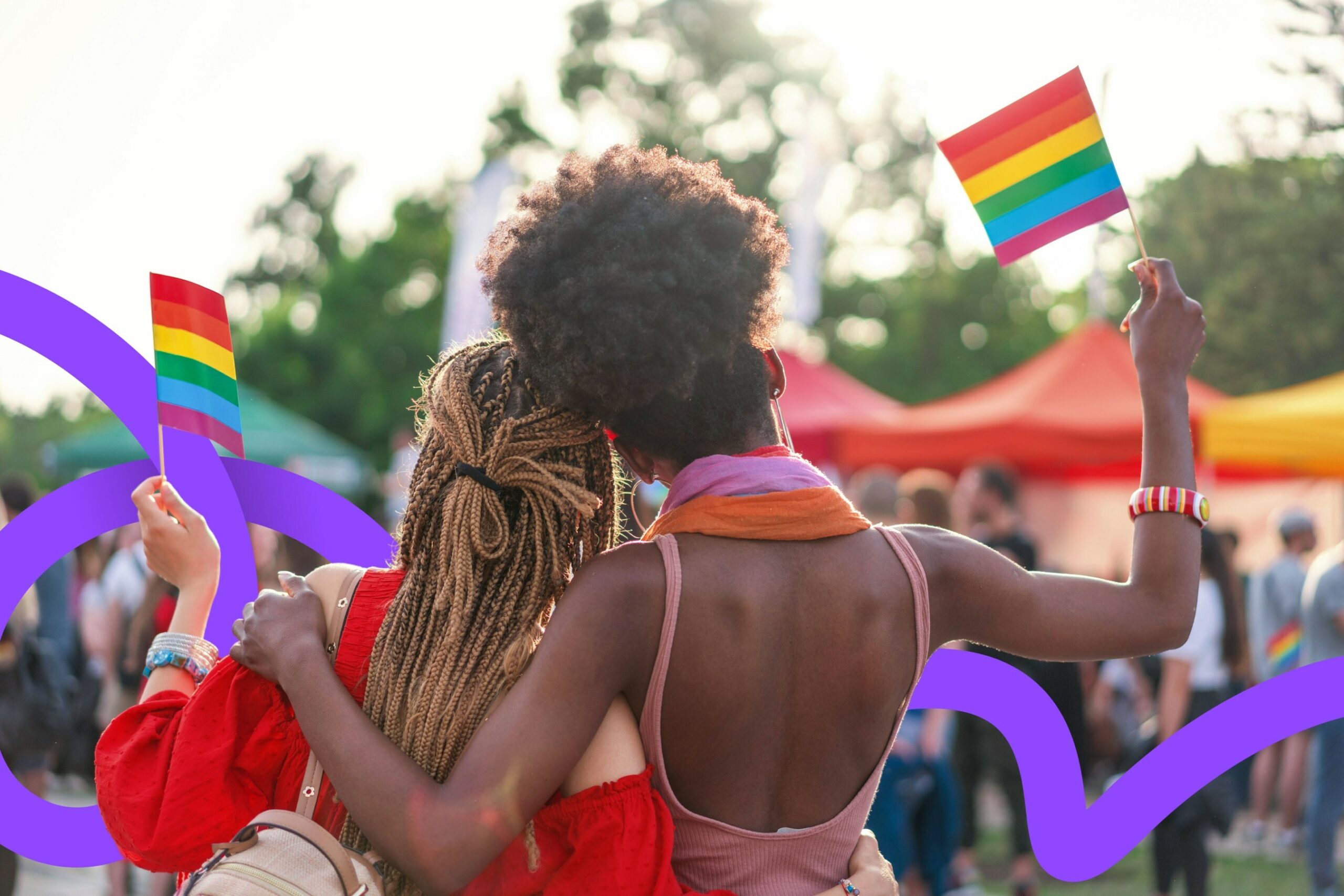 Young couple embracing each other and waving flags at pride rally.