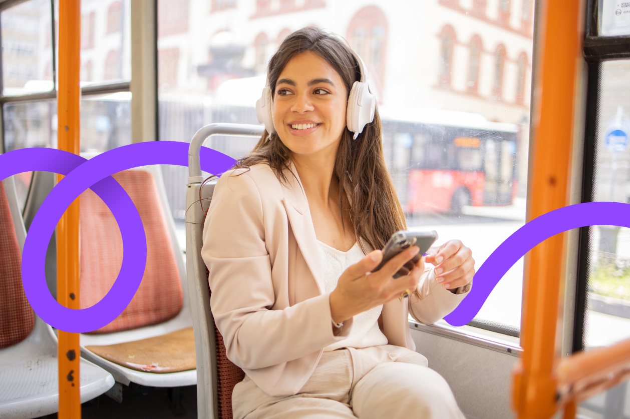 Woman on phone smiling with headphones on bus