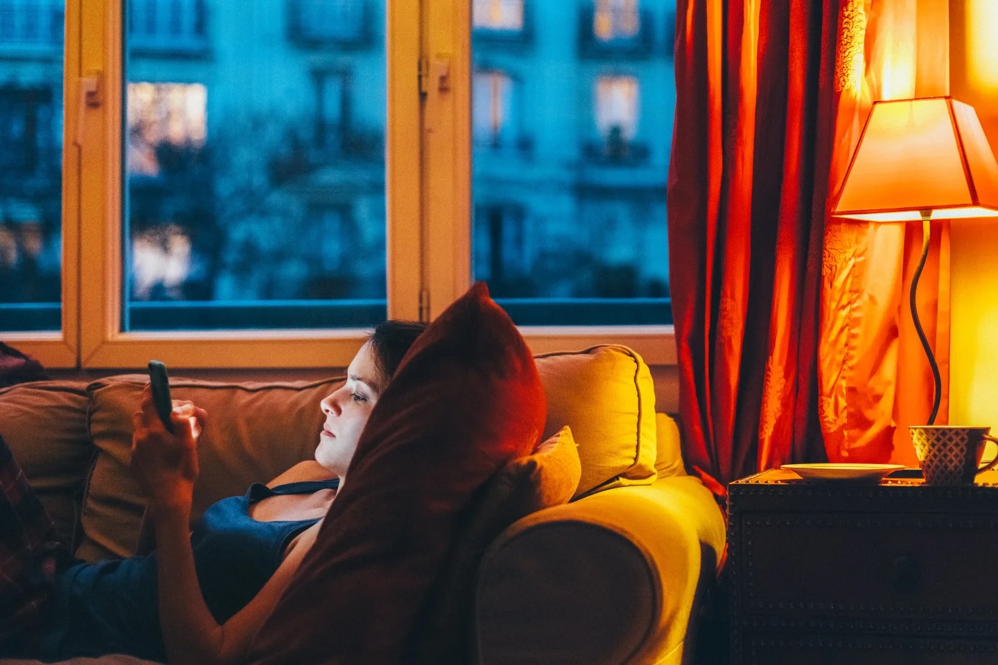 Woman laying cozily on the couch on her phone
