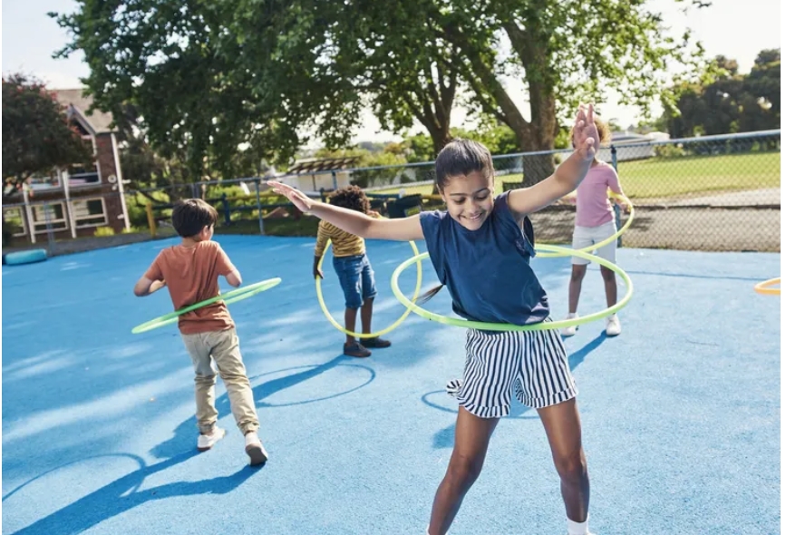 Kids hoola-hooping on a playground for recess