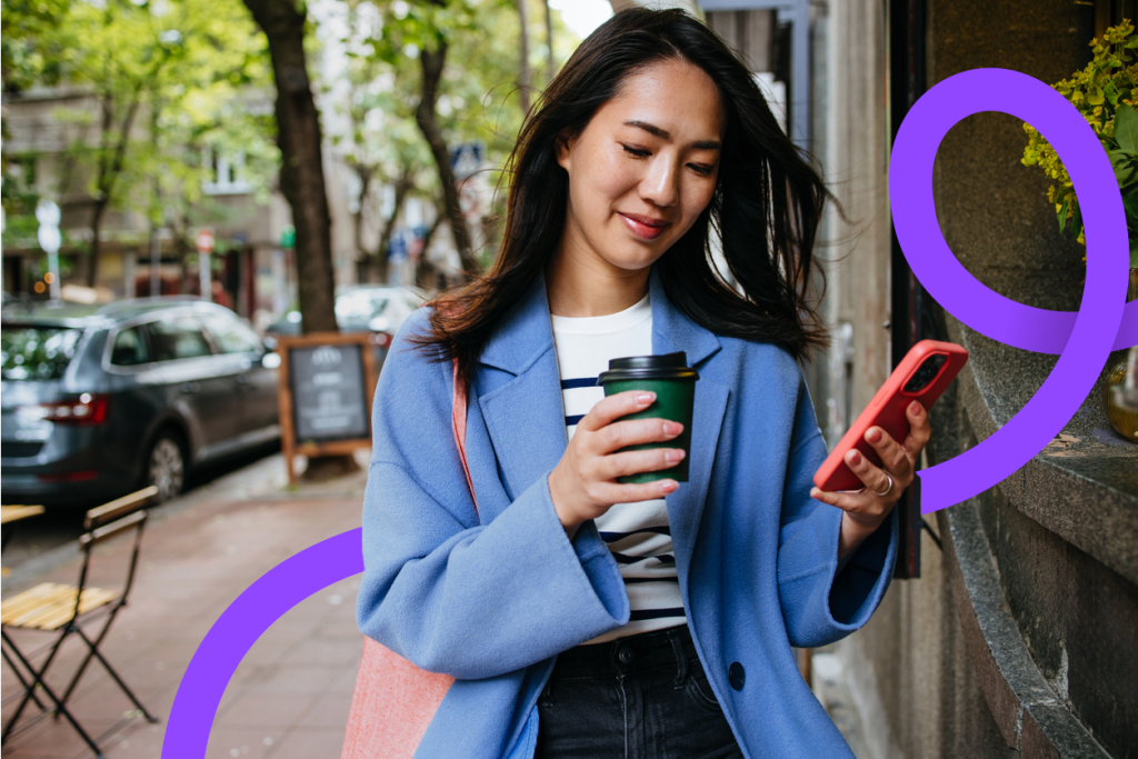 Young woman walking with a coffee and her phone
